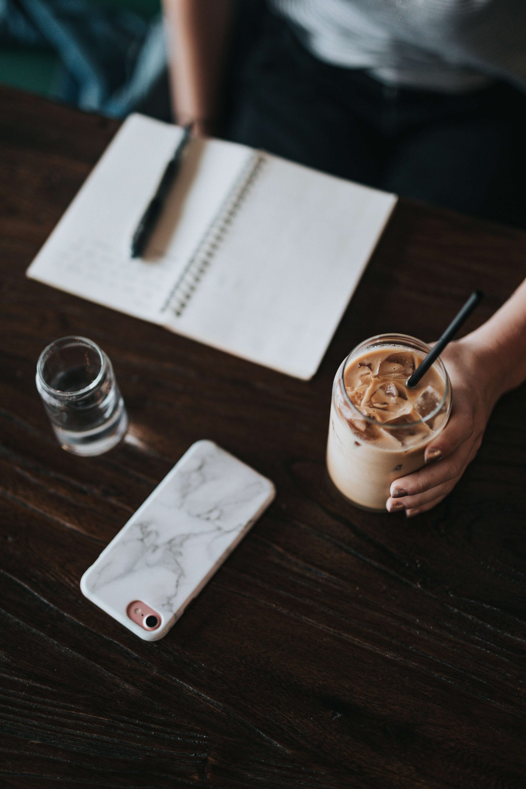 Notebook, Coffee and Phone on Brown Table